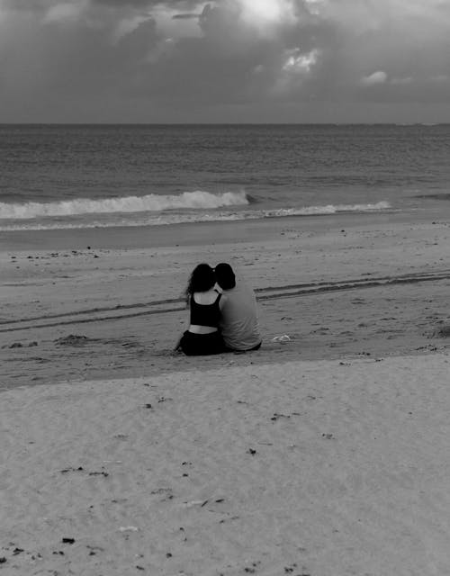 Couple Sitting Together on Beach in Black and White