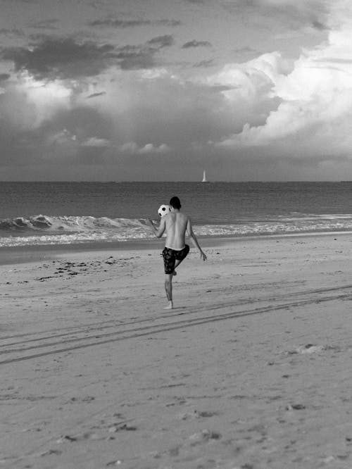 Man Playing Football on Beach