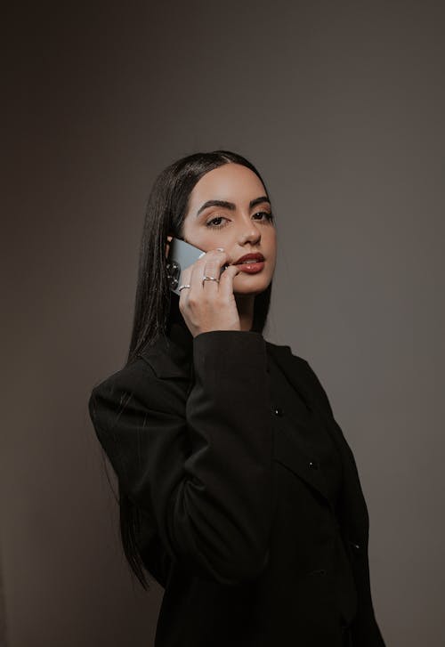 Studio Shoot of a Brunette Using Phone against Gray Background