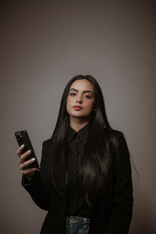Studio Shoot of a Brunette Woman Using Phone against Gray Background