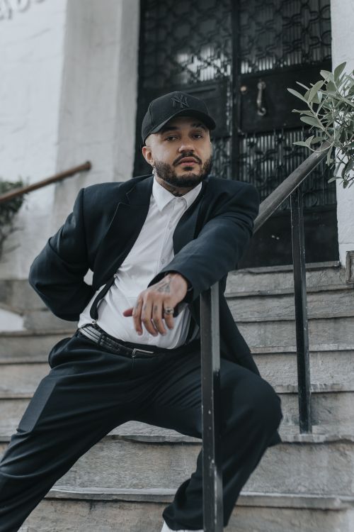 Free Confident man in a stylish suit and cap poses on city steps, showcasing urban fashion. Stock Photo