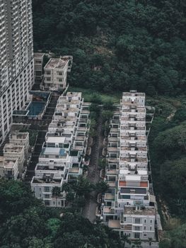Aerial view of urban residential housing complex next to lush green forest