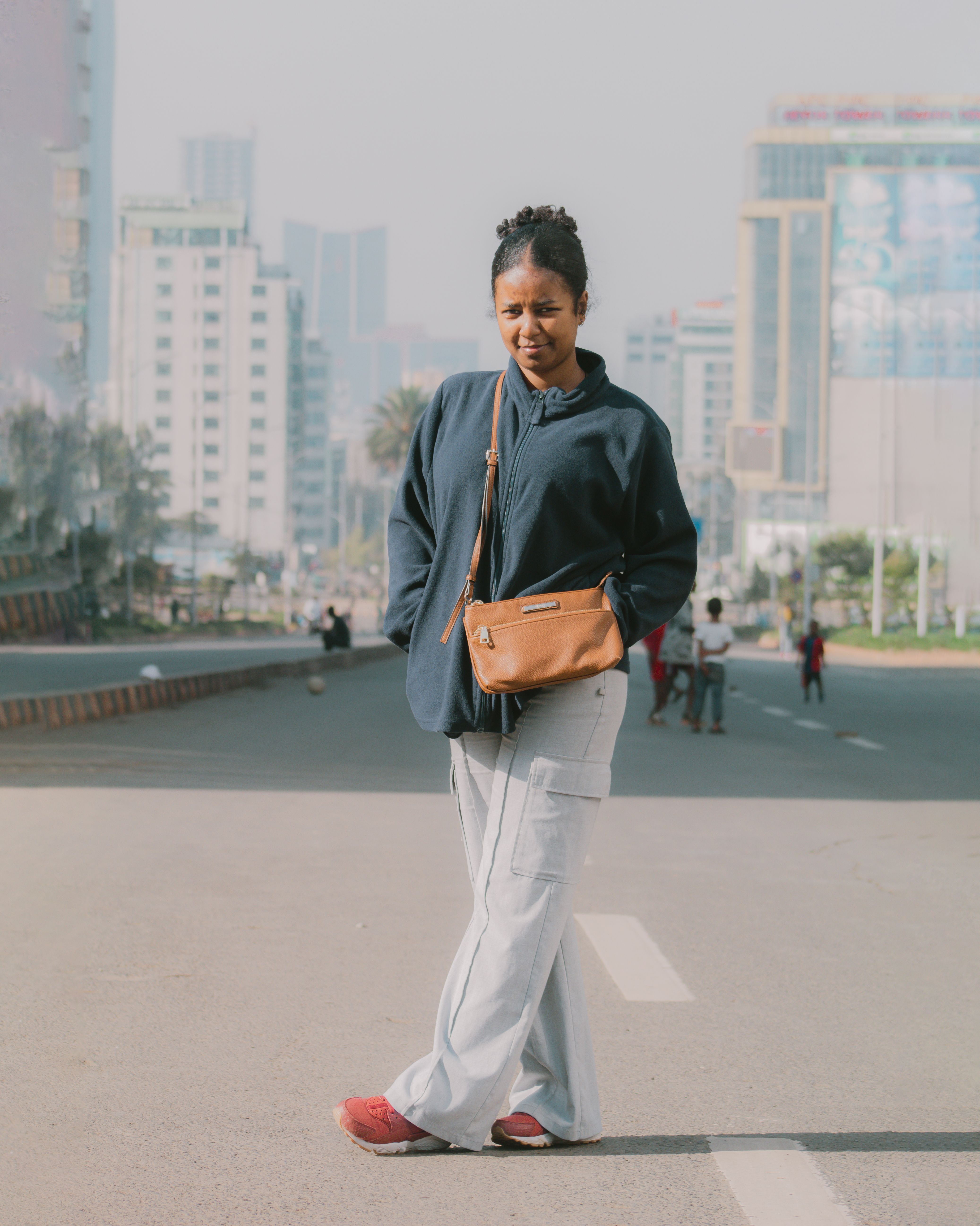 A woman in stylish streetwear poses on a busy street in Addis Ababa, Ethiopia.