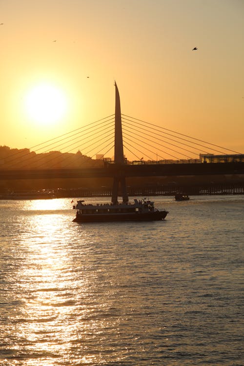 Silhouetted Golden Horn Bridge and a Boat on the Bosphorus in Istanbul at Sunset