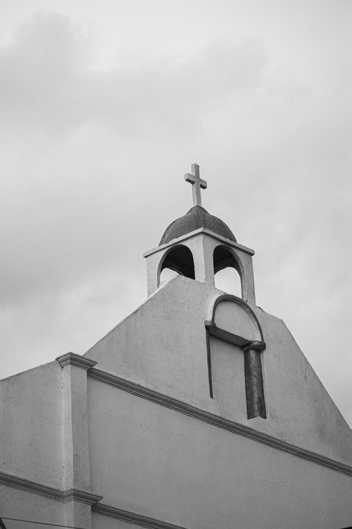 Free Black and white image of a church facade with a prominent cross under an overcast sky. Stock Photo
