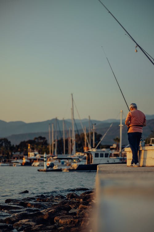 Man Fishing with a Rod at a Sea Harbor