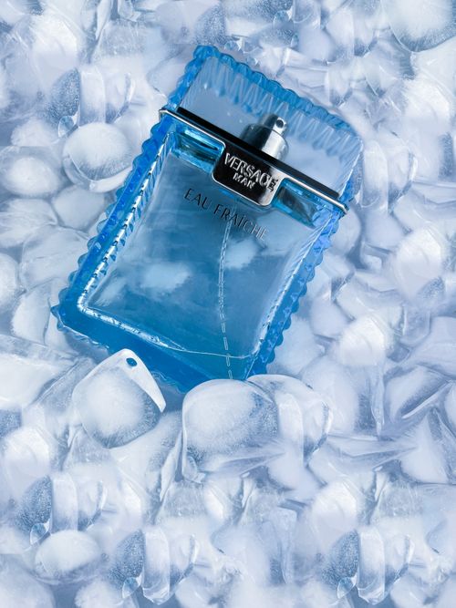 Free A luxurious Versace Eau Fraiche perfume bottle surrounded by ice cubes, showcasing elegance and freshness. Stock Photo