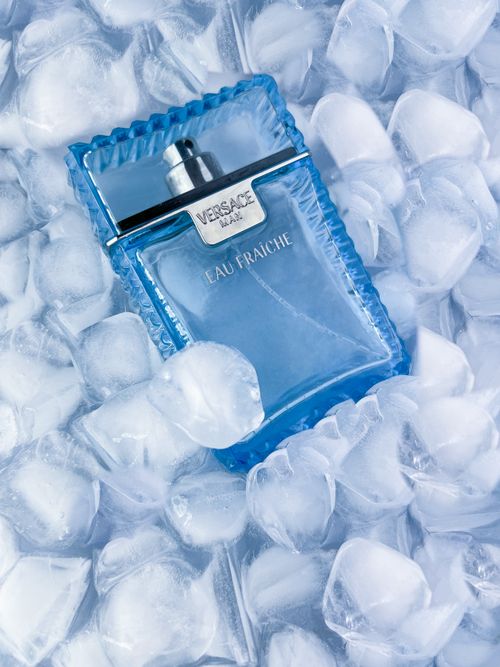 Free Luxury Versace Eau Fraiche fragrance bottle surrounded by ice cubes, showcasing elegance and freshness. Stock Photo