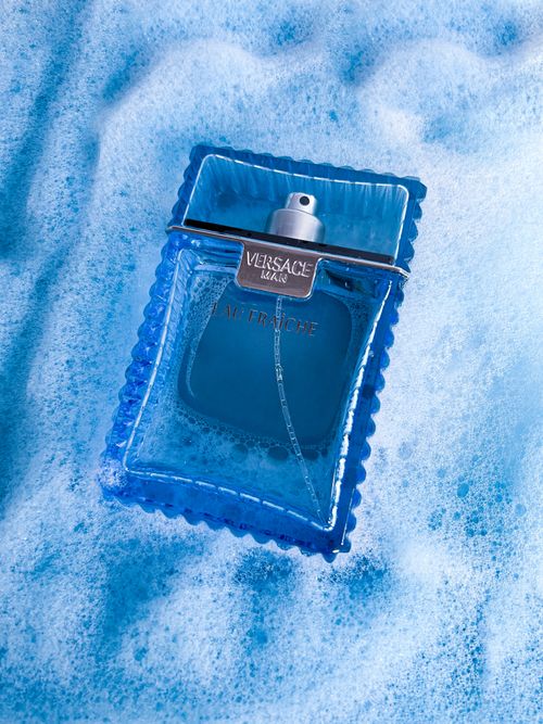 Free A Versace Eau Fraiche perfume bottle elegantly resting in blue foam, conveying luxury and freshness. Stock Photo