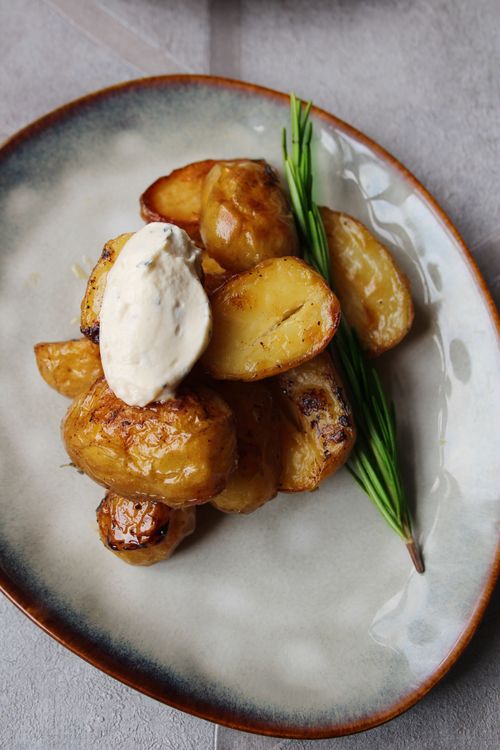 Free Delicious roasted potatoes garnished with sour cream and chives on a ceramic plate. Stock Photo