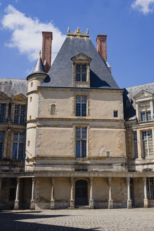 Free Sunlit facade of the historic Fontainebleau Palace, showcasing Renaissance architecture in France. Stock Photo