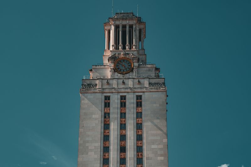 University of Texas clock tower against a teal sky in Austin