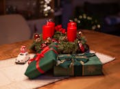 圣诞场景温馨舒适，木桌上摆放着红蜡烛、礼物和装饰品