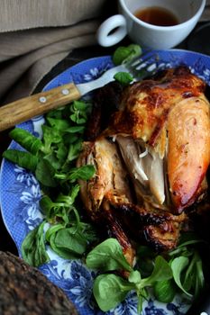 Mouthwatering roasted chicken on a floral plate with fresh leafy greens, perfect for dinner.