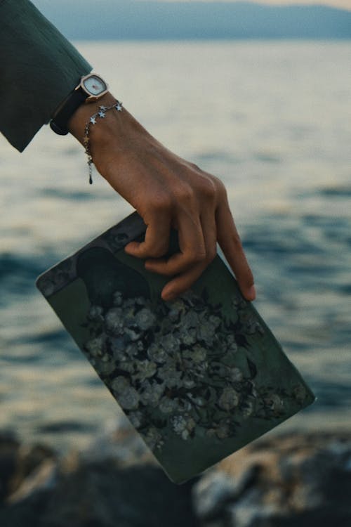 Woman Hand Holding Notebook over Water