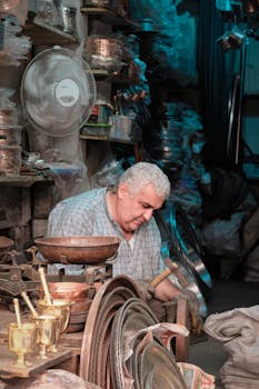An artisan meticulously working with metal tools in a cluttered workshop, showcasing traditional craftsmanship.