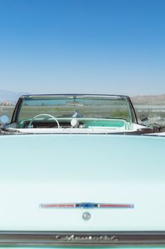 Classic Chevrolet convertible under a clear blue sky with a desert backdrop.