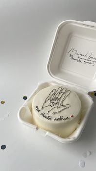 Close-up of a modern white cake with unique hand design, perfect for celebrations.