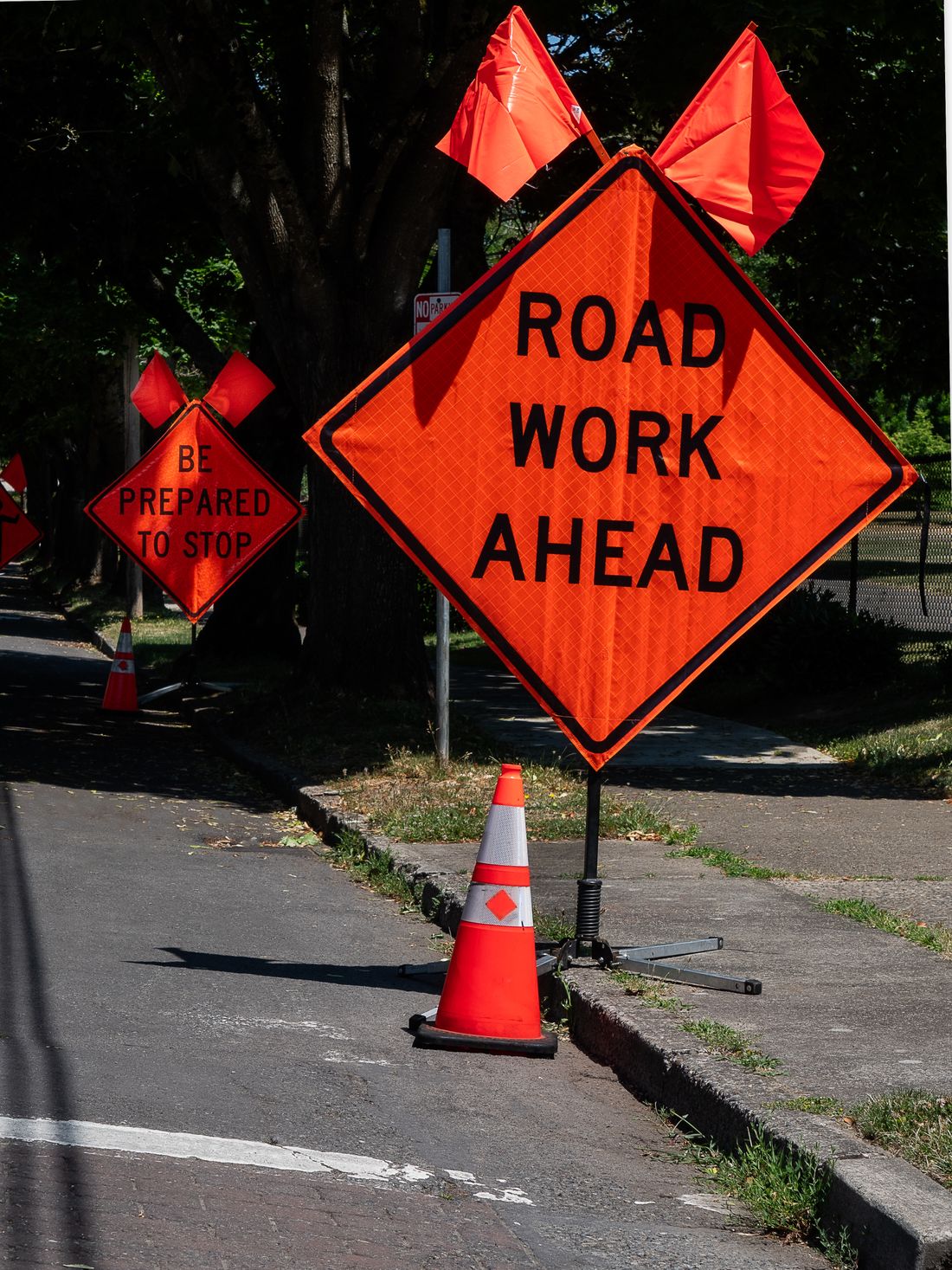 Orange Road Work Ahead and Be Prepared to Stop signs on a street
