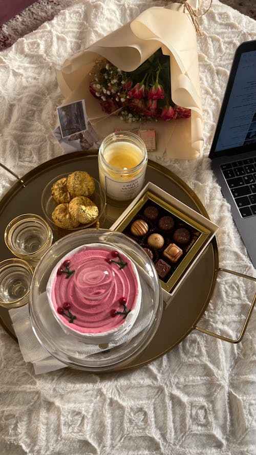 Sweets and Candles on a Tray Standing next to a Bouquet and a Laptop 