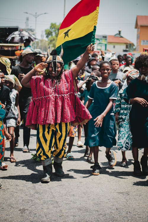 View of a Crowd Walking on a Street with a Flag of Ghana and Smiling 