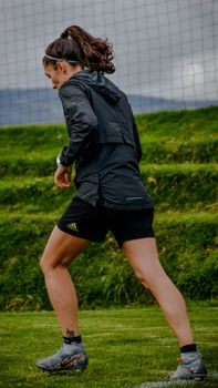 Woman in sportswear training on a grassy field, showcasing athleticism.