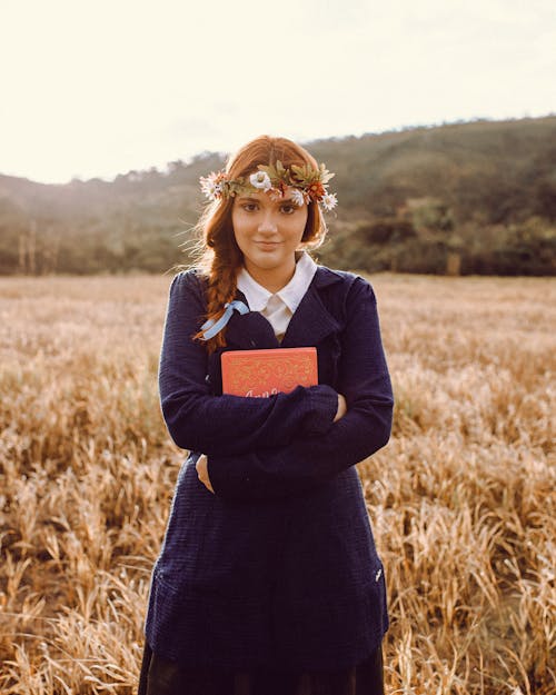 Photo of a Student Wearing a Wreath and a School Uniform in Meadow
