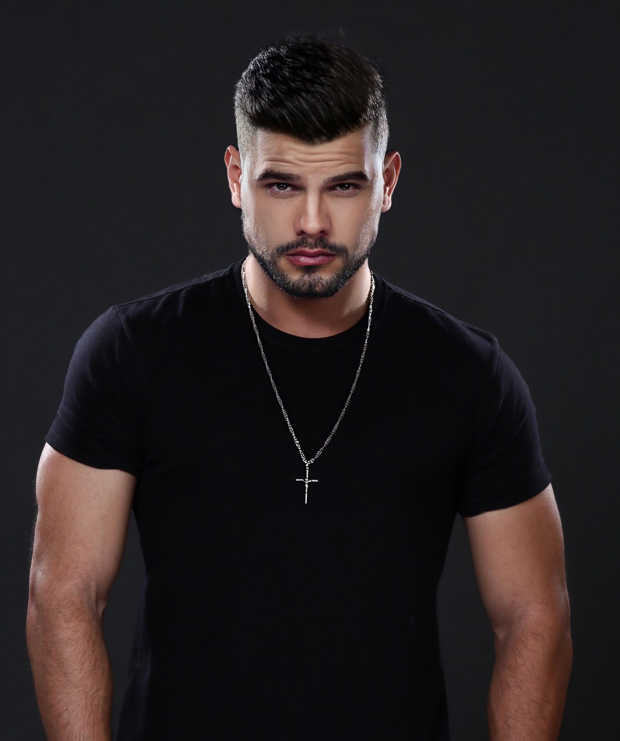 Close-up studio portrait of a fashionable man wearing a black t-shirt and jewelry.