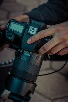 A person holding a professional camera, adjusting settings outdoors.