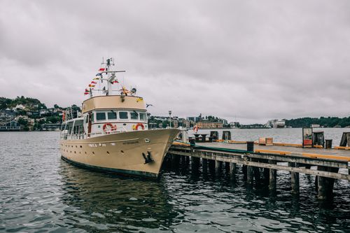 Free Elegant yacht moored at a scenic harbor with overcast skies, cityscape in the background. Stock Photo