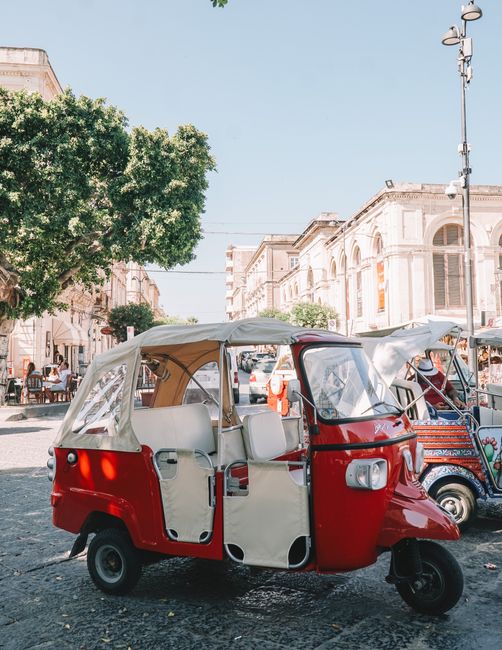 Colorful tuk-tuk in the historic city of Siracusa, Sicily, showcasing vintage architecture and charm.