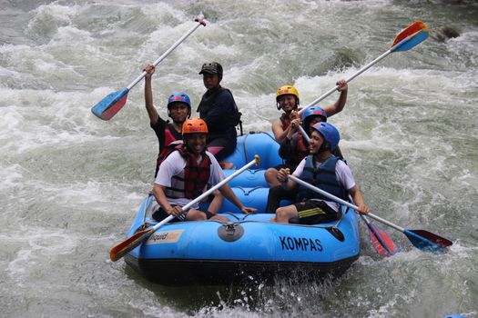 Group enjoying thrilling white water rafting on a river in Yogyakarta, Indonesia.