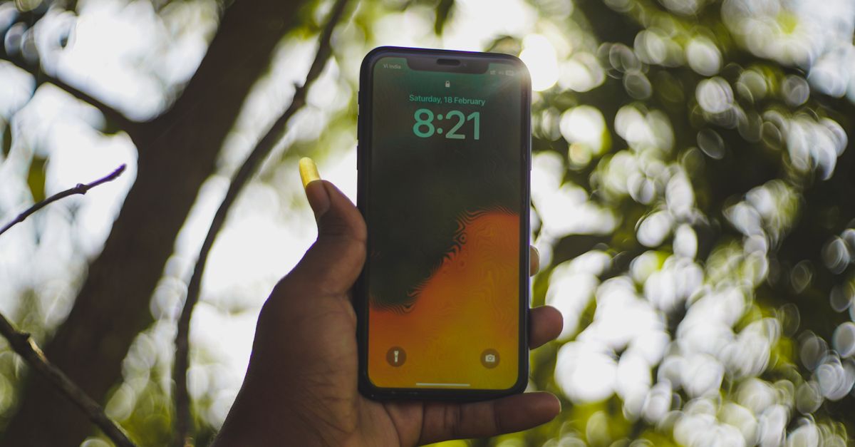 person holding smartphone with church in background, warm light