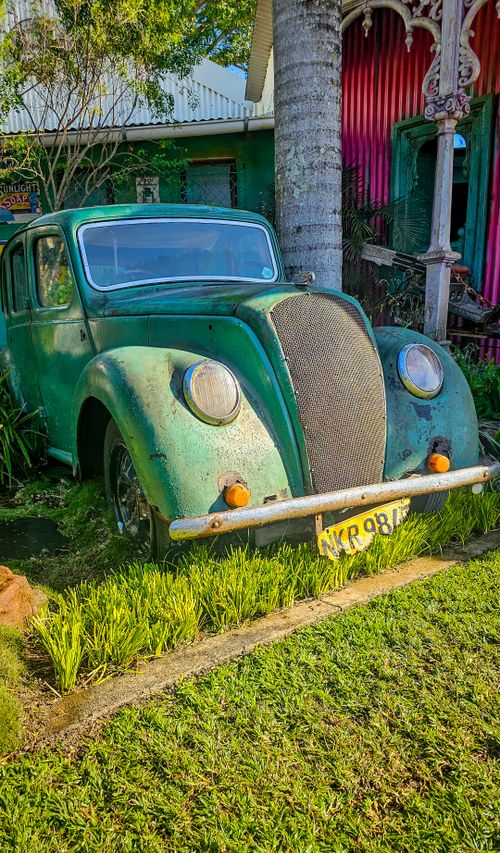Free A vintage Morris Eight car sits sunlit in a garden, showcasing classic automotive design and rustic decay. Stock Photo