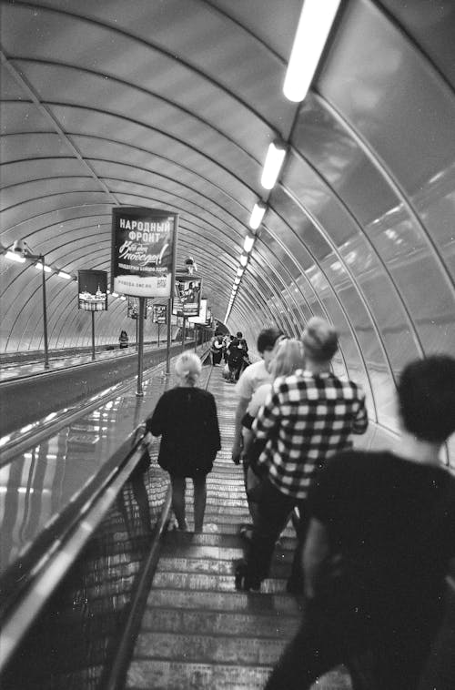 A black and white photo of people walking down an escalator