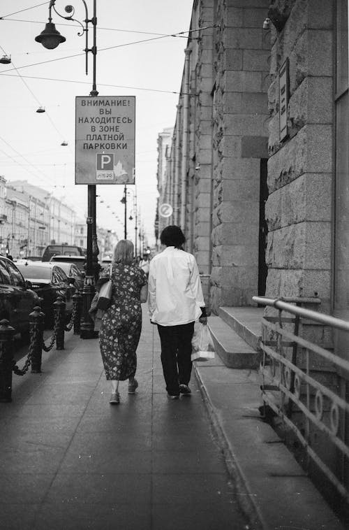 Two women walking down a sidewalk in a city