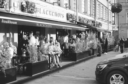 Free Black and white street view of a bustling café in Saint Petersburg, Russia, showing vibrant city life. Stock Photo