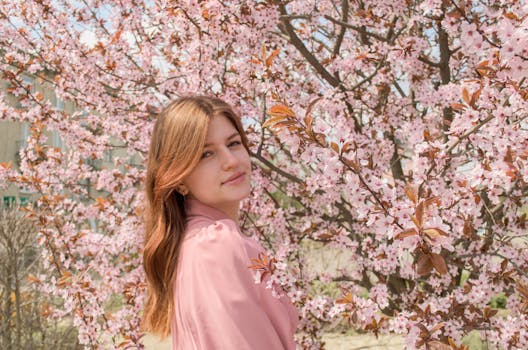 Young woman enjoying springtime in a cherry blossom garden.