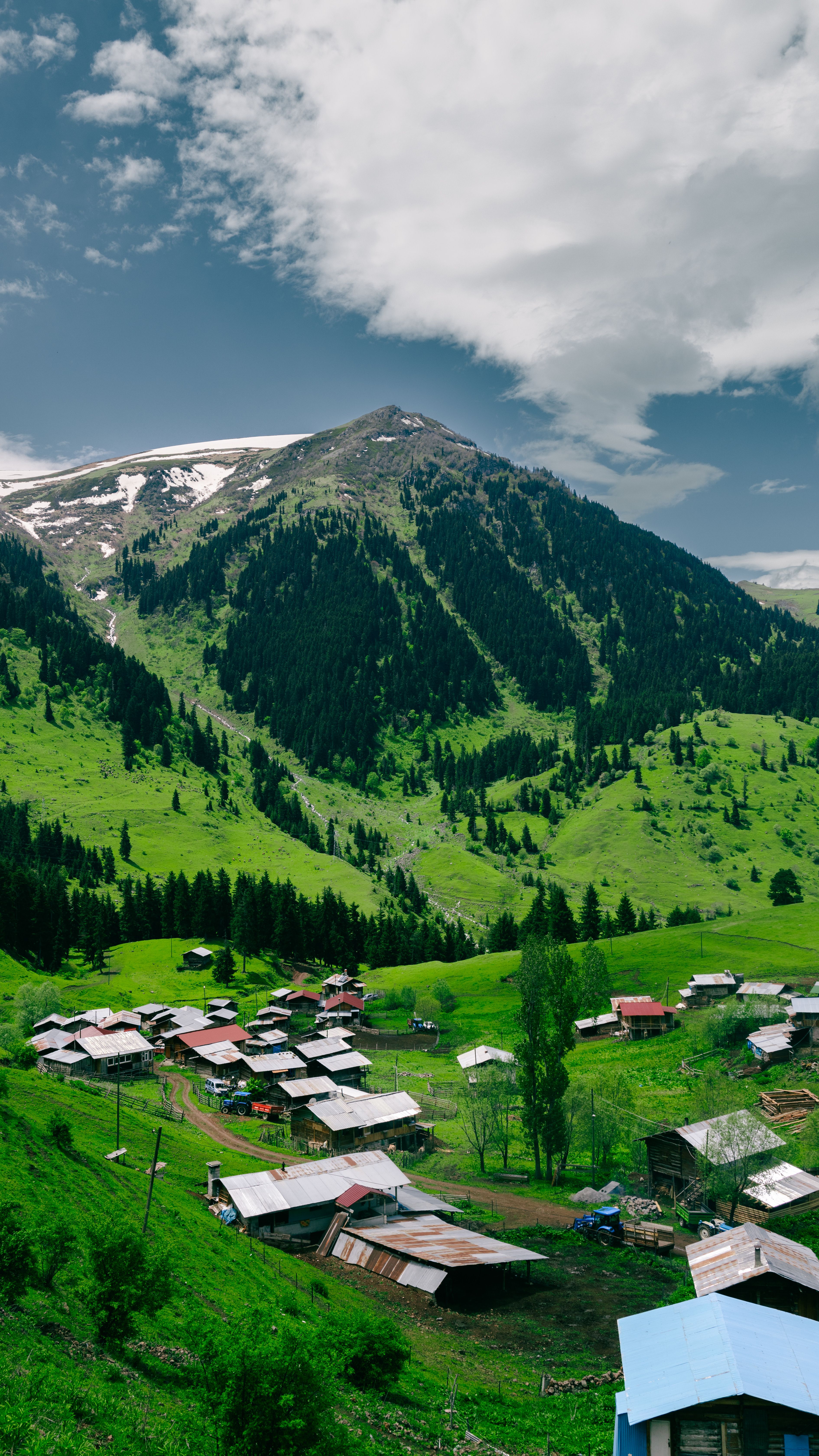 Charming mountain village surrounded by lush green hills under a cloudy sky, perfect for travel inspiration.