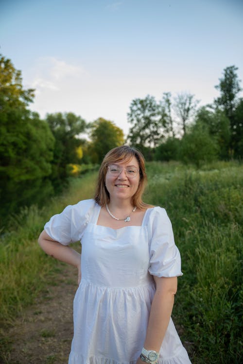 Woman in a White Dress Standing on a Path in the Countryside 
