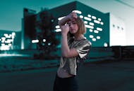 黄昏时分，一位身穿金属上衣的时尚女性在现代城市中自信地摆姿