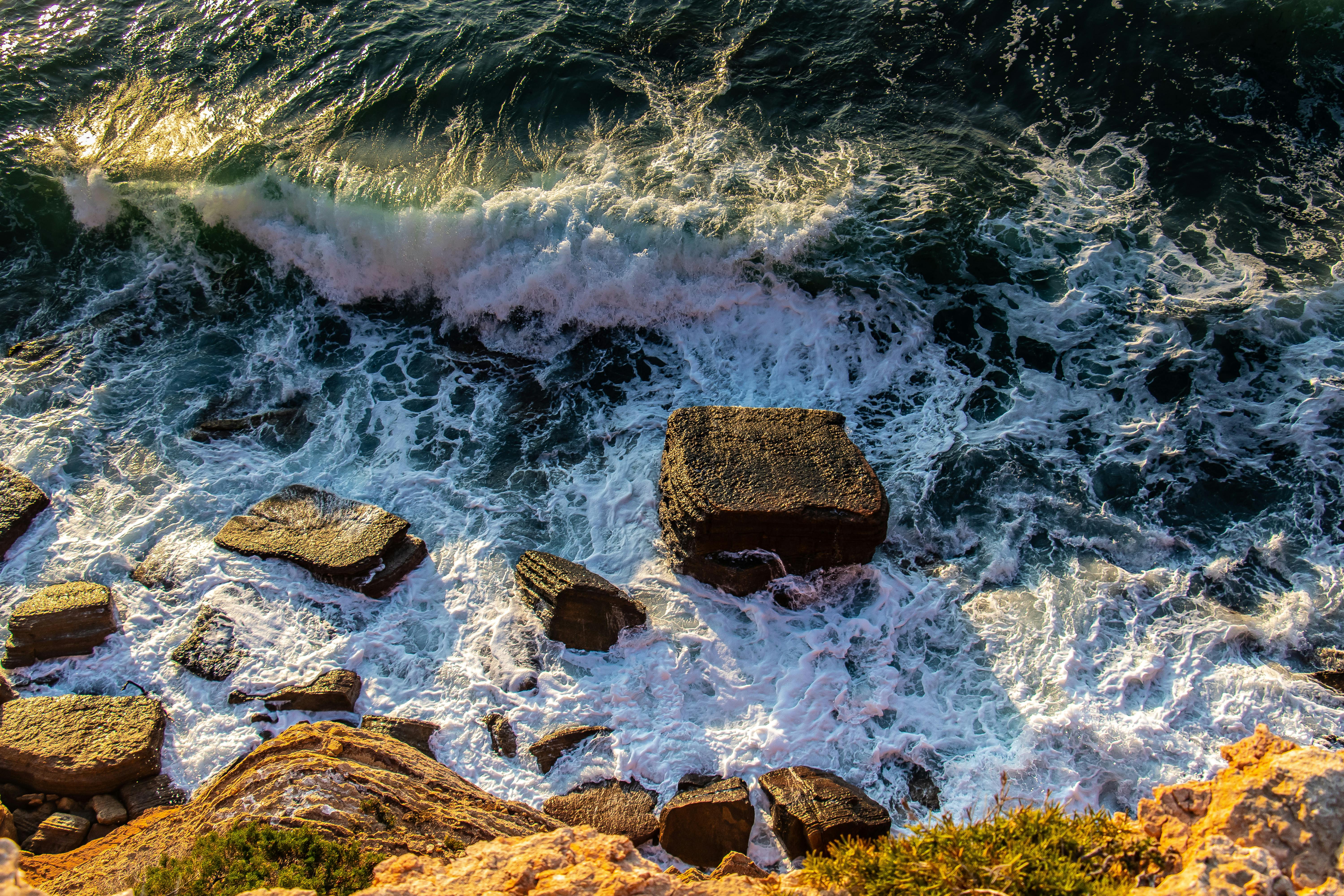 Captivating aerial view of waves crashing on rugged rocks and cliffs in Korbous, Tunisia.