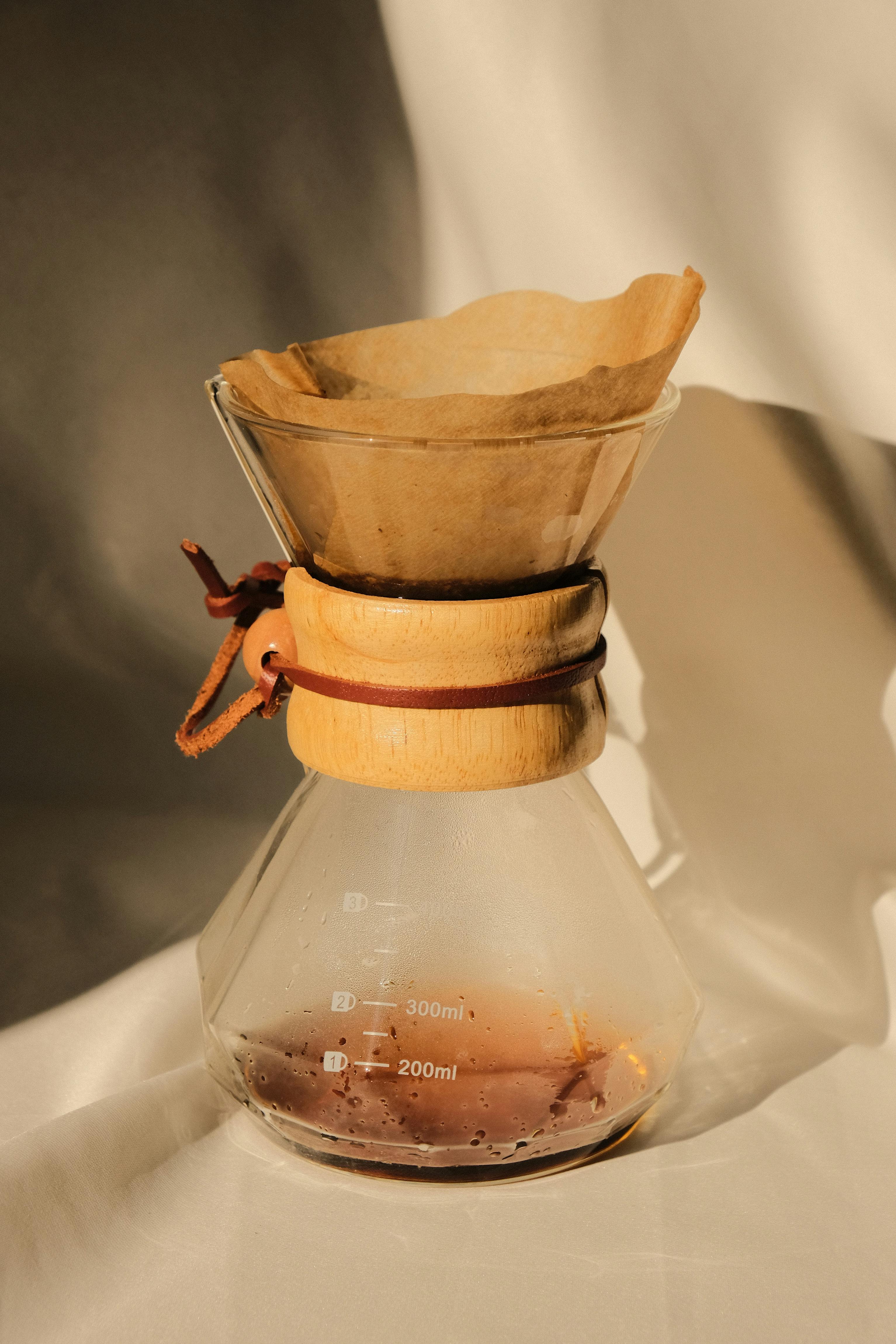 A stylish Chemex coffee maker with grounds and liquid, beautifully captured in sunlight.