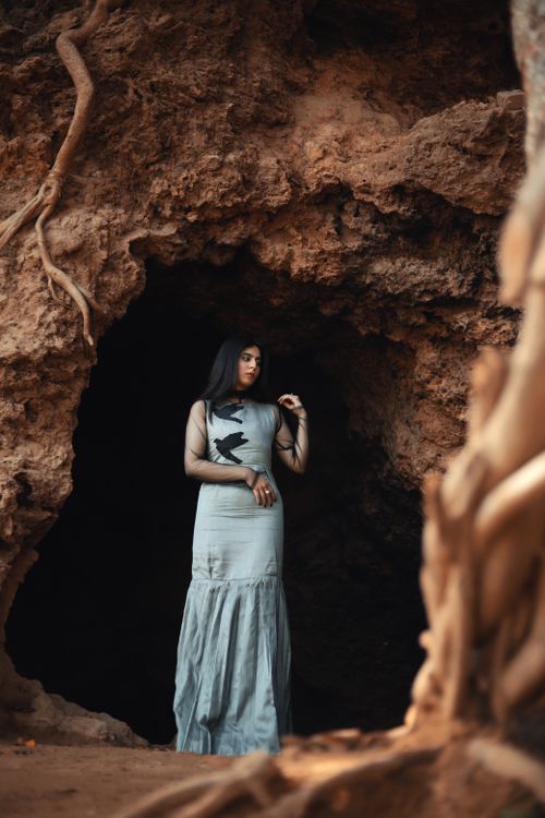 Free A model poses in a silver dress near a cave entrance, evoking elegance and mystery. Stock Photo