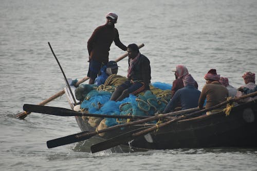 Group of Men Sitting on a Rowboat with a Fishing Net 