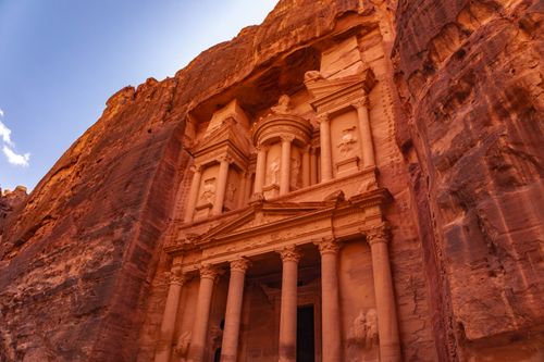 Free Explore the iconic Treasury at Petra, Jordan, bathed in warm, golden light against the rock cliffs. Stock Photo