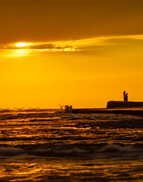 Free Silhouette of a couple on Novigrad pier against a stunning golden sunset. Stock Photo