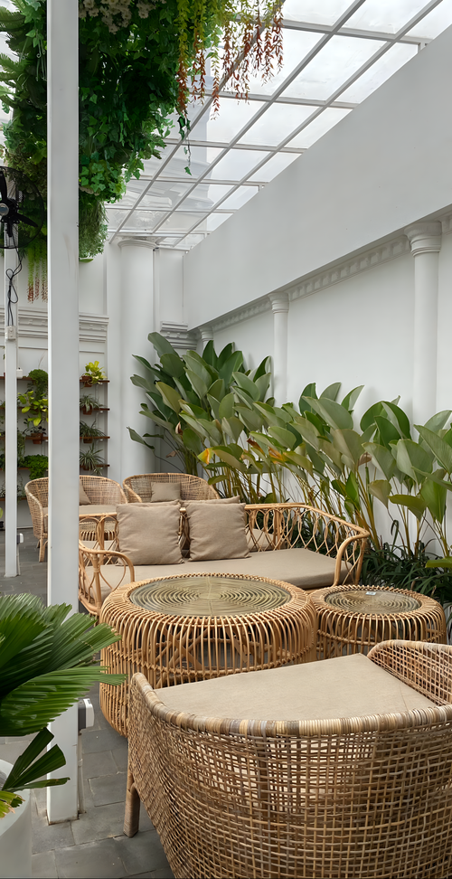 Free Relaxing indoor garden patio with wicker furniture and lush plants. Stock Photo