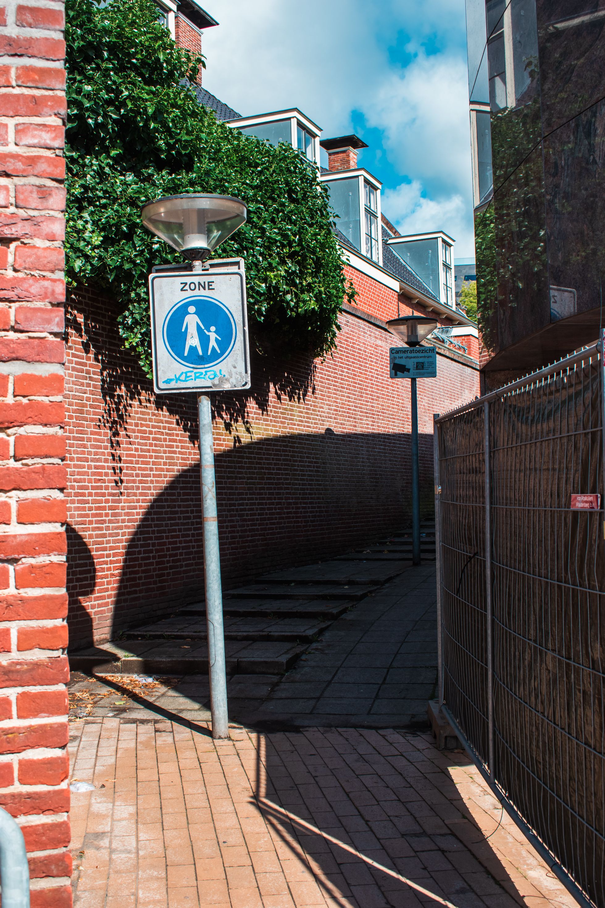 Brick pathway with pedestrian signs in a sunny urban area.
