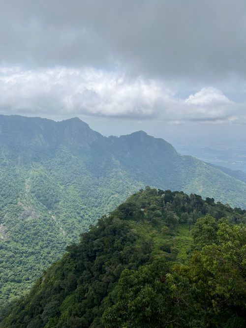 Free Explore this breathtaking view of lush green mountains under a cloudy summer sky. Stock Photo
